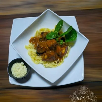 Plate of pasta with meat sauce, garnished with basil leaves, served with grated cheese on the side.
