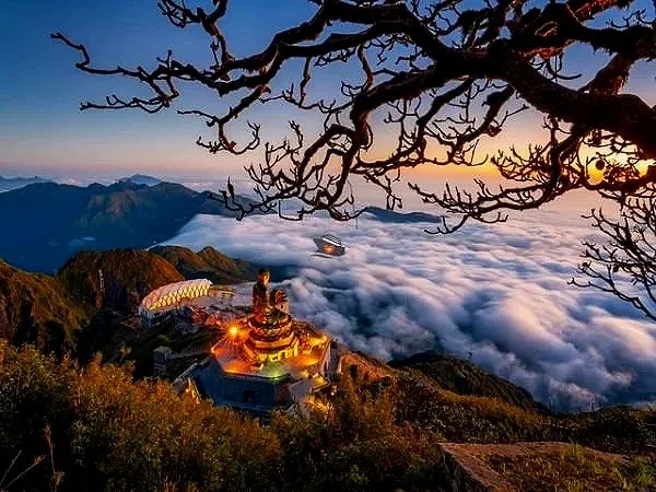 A mountain scene at sunrise with a temple, a helicopter flying above a sea of clouds, and a tree branch in the foreground.