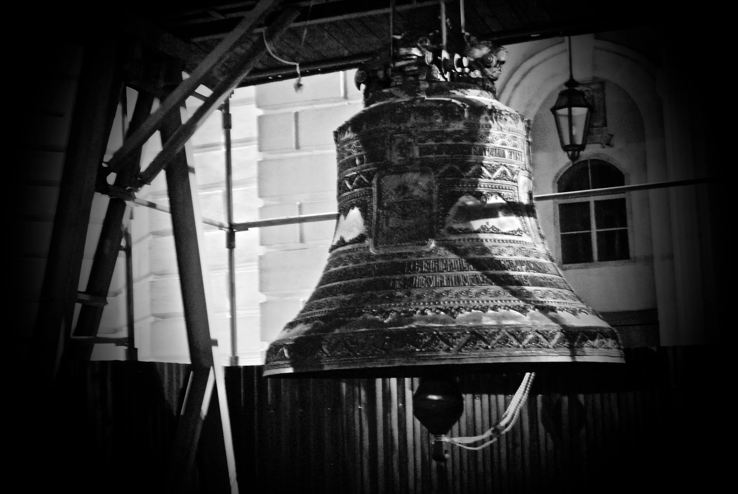 A large, ornate bell hanging inside a building, surrounded by scaffolding and construction materials.