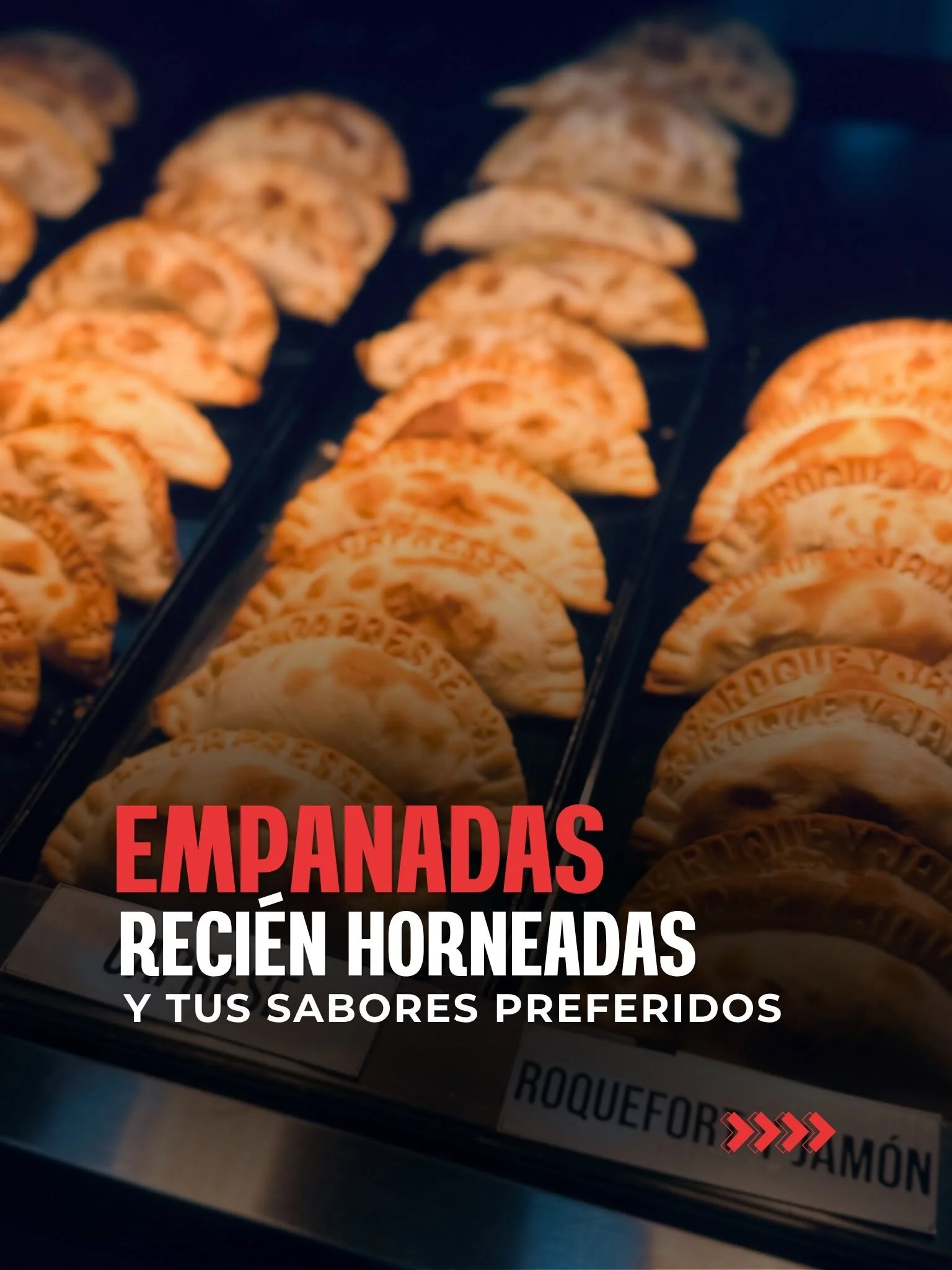 Close-up of a display case filled with freshly baked empanadas with a sign in Spanish indicating they are freshly baked, with a focus on their golden crusts and various flavors.