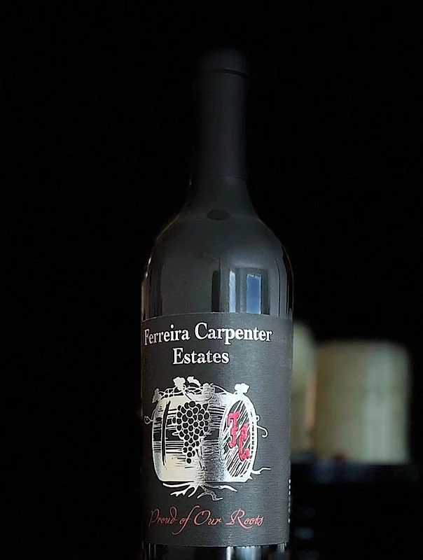A bottle of Ferreira Carpenter Estates red wine with a dark label featuring a vineyard illustration and the text "Ferreira Carpenter Estates," "Proud of Our Roots" in red, and a pink initials "FC."