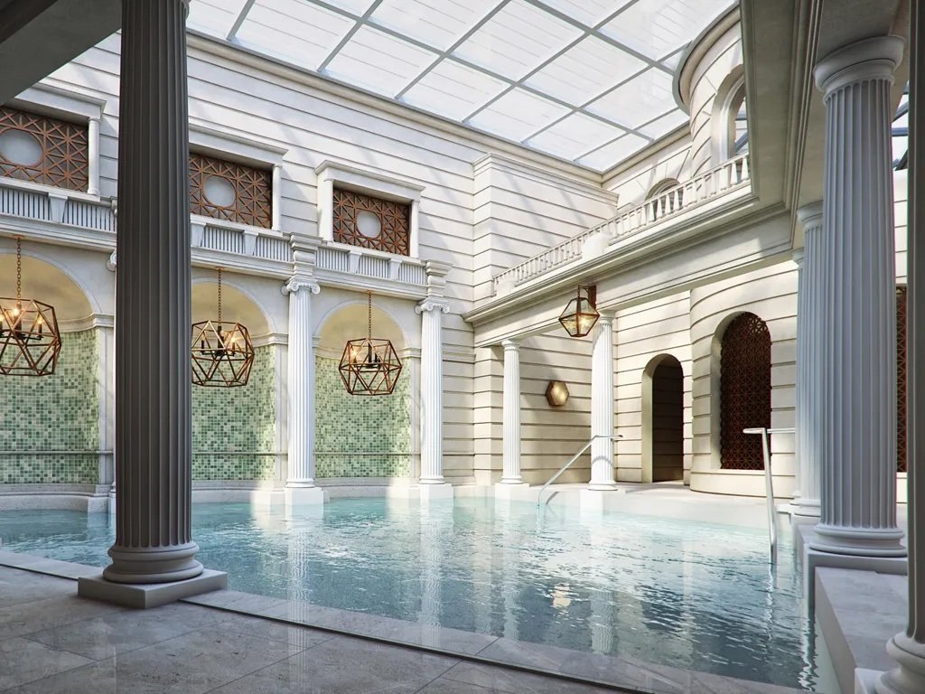Indoor swimming pool area with classical architectural features, white columns, and a glass ceiling.