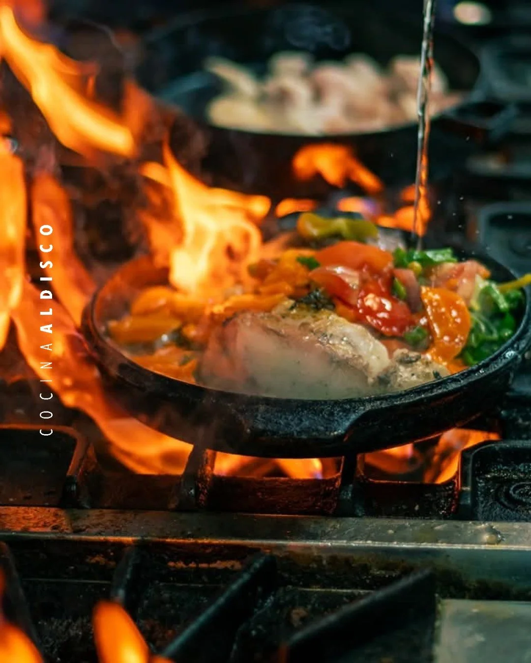 Cooking vegetables in a cast iron skillet over an open flame on a stove.