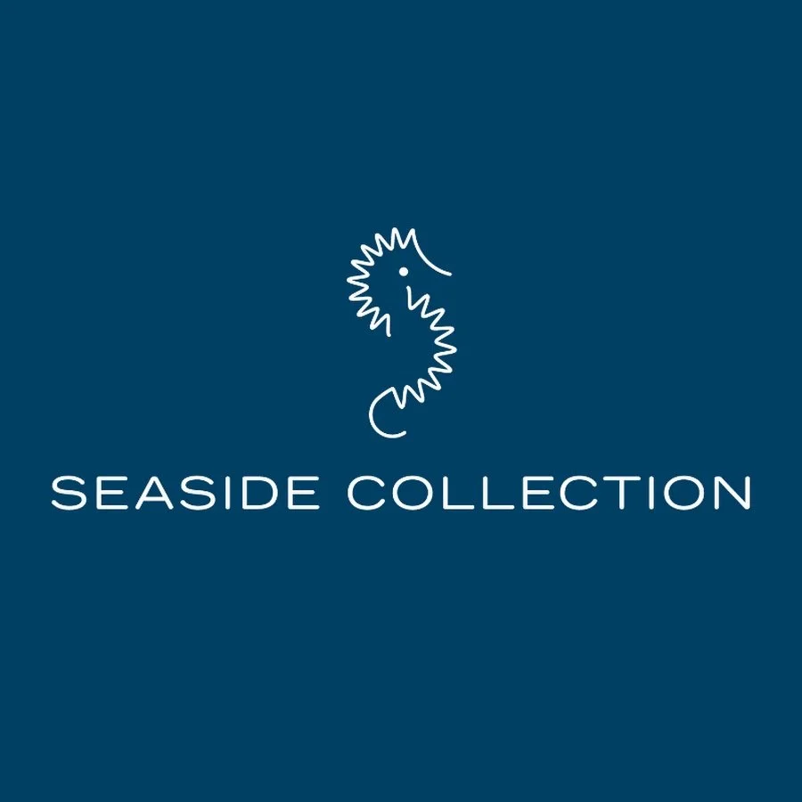 Logo for Seaside Collection featuring a simple white line drawing of a seahorse on a dark blue background with the text 'SEASIDE COLLECTION' below it.