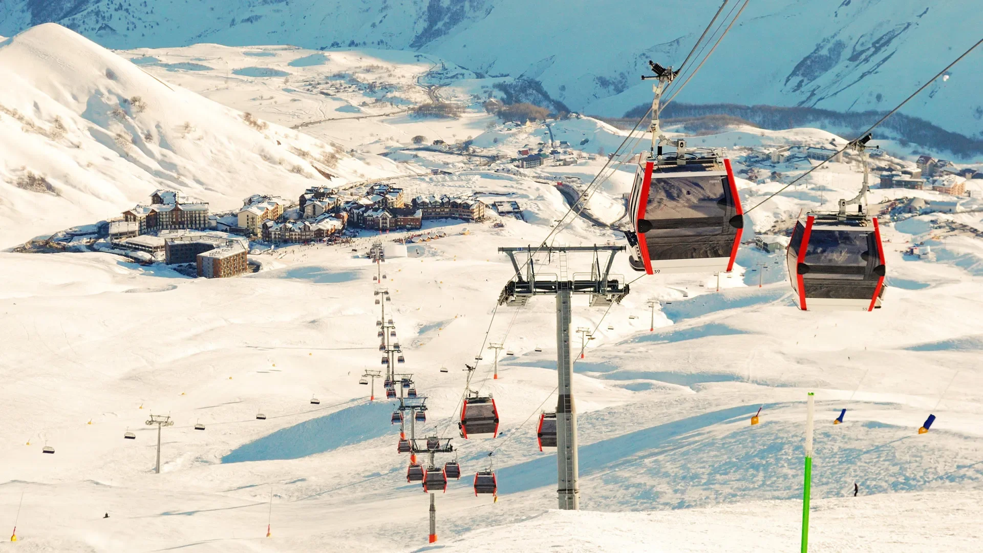Snow-covered ski resort with ski lifts, cabins, and mountain scenery.