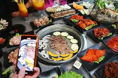 A Korean BBQ meal with sliced meats, vegetables, and various side dishes on a table.
