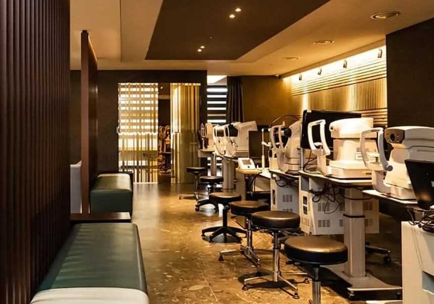 A row of medical testing equipment on desks in a modern, well-lit lab or clinic with black and wood decor and seating area.