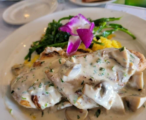 Plate of chicken with mushroom and herb cream sauce, served with green beans, broccoli, and purple pickled onions.