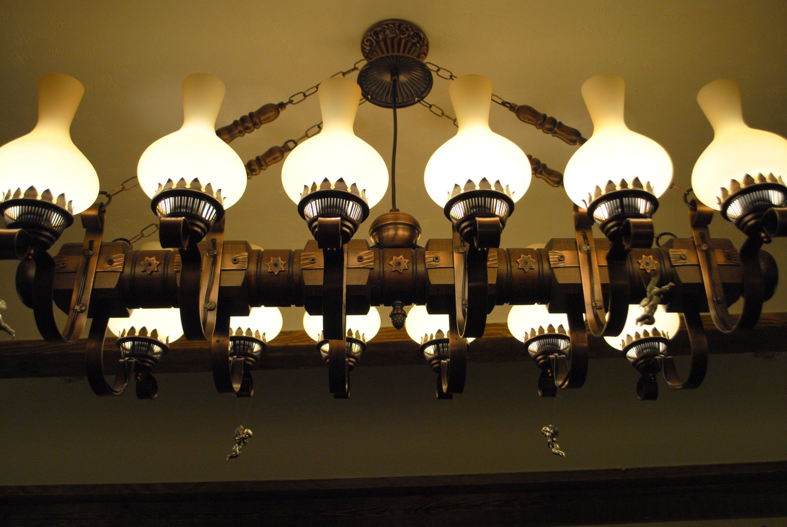 Close-up of a vintage chandelier with frosted glass shades and ornate wooden and metal detailing.