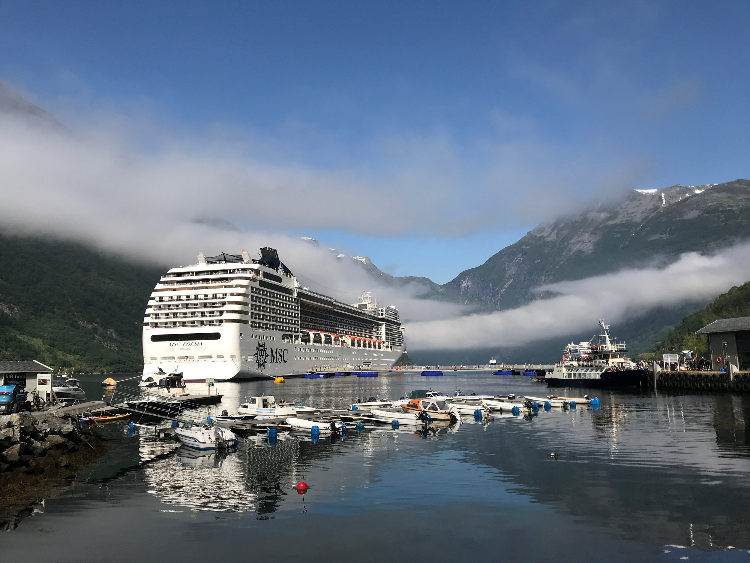 Large white cruise ship with multiple decks sailing on calm water under cloudy sky, named Costa Diadema.