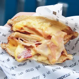 A breakfast sandwich with melted cheese, ham, and eggs on toasted bread