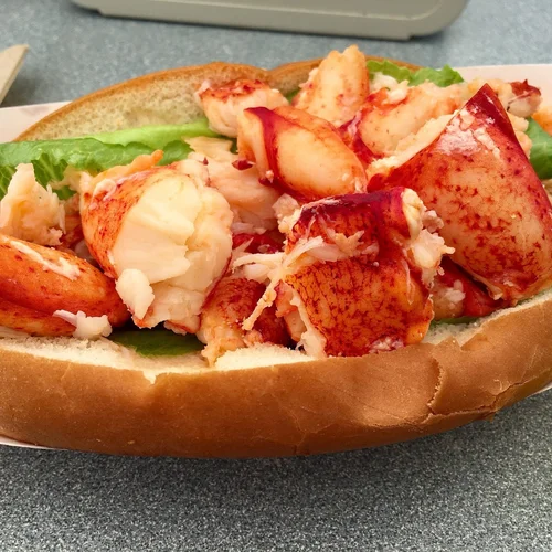 Lobster roll sandwich with chunks of lobster, lettuce, and a toasted bun.