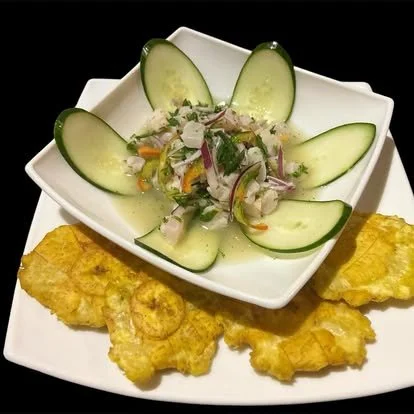 Fried fish fillets with cucumber salad on a white plate.