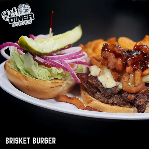 Close-up of a brisket burger with toppings and sides on a white plate, with a black background and a restaurant logo in the top left corner.