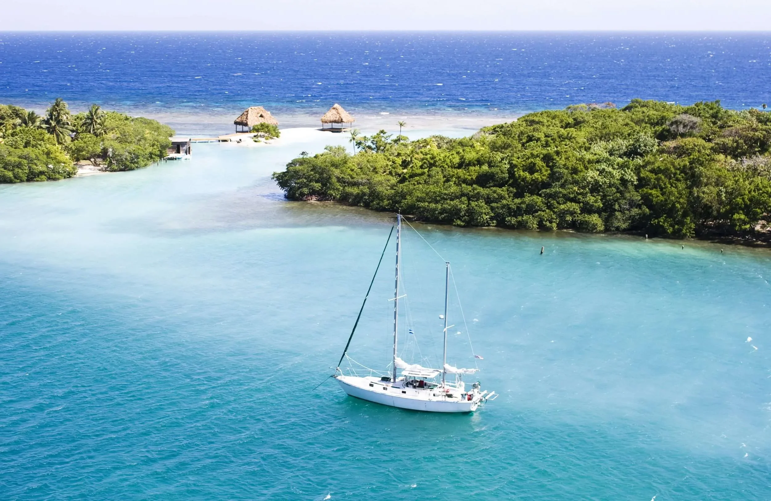 Sunny-Day-with-Brilliant-Blue-Water-and-Sailboat-in-Roatan-Honduras-scaled.webp