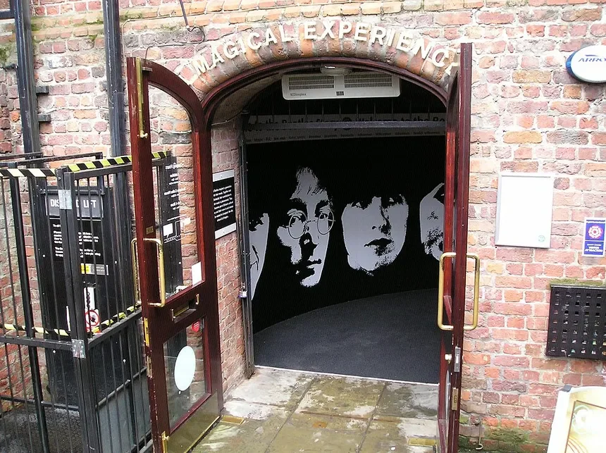 Entrance to the Magic Ale Experience with brick wall, open door, and mural of three faces inside.