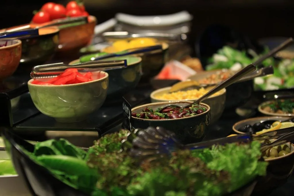 A variety of bowls filled with fresh vegetables and salads on a buffet table.