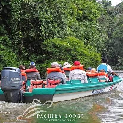 A group of people on a boat with orange life jackets, traveling on a river surrounded by green trees in Costa Rica.