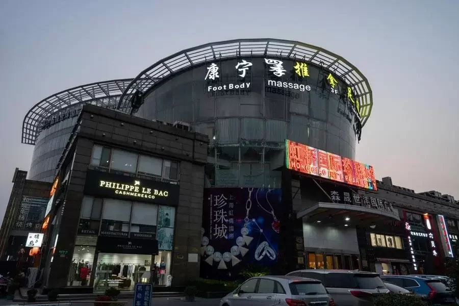 Multi-story shopping mall or commercial building with illuminated signs, including a jewelry store named Philippe Le Bac, and a large digital billboard.