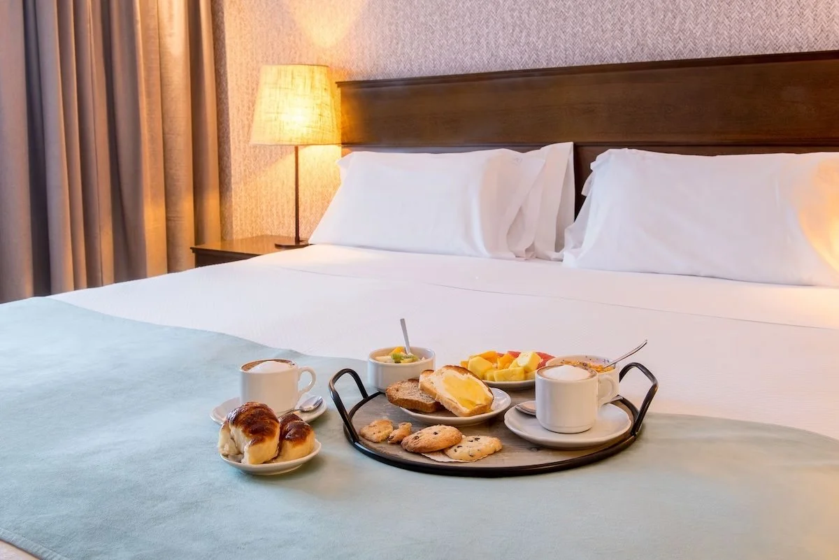 Breakfast tray on a bed with a lamp and pillows in a hotel room.