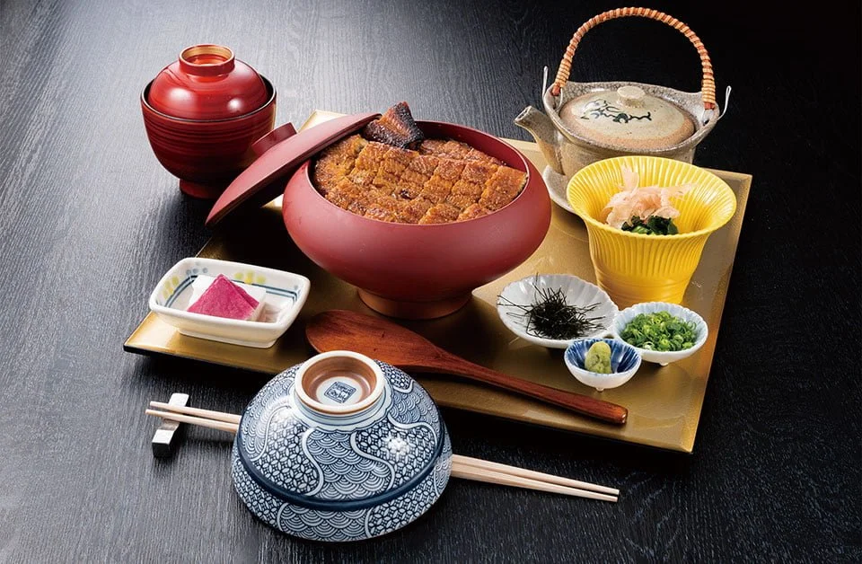 Traditional Japanese meal with bowls of rice, miso soup, pickles, seaweed, green onions, and a teapot, all arranged on a tray with chopsticks.