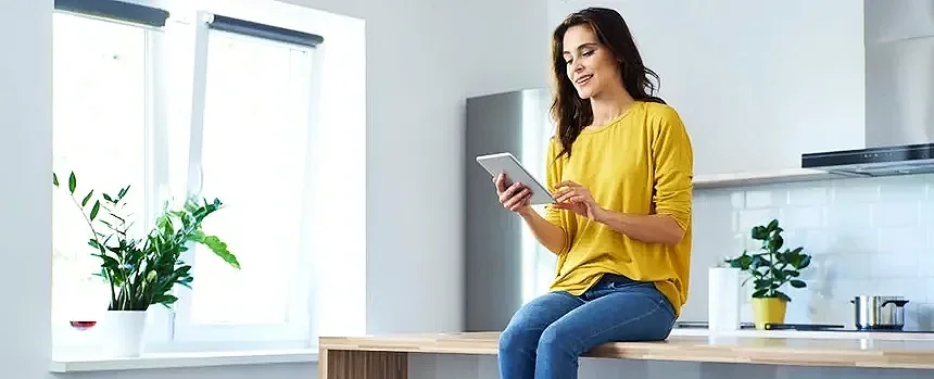 Two dogs, a small black and white one and a larger golden retriever, sitting inside a house in front of a large window. There is a welcoming sign for puppies with the names Ellie and Archer, and a jar of treats on a gold table between the dogs.