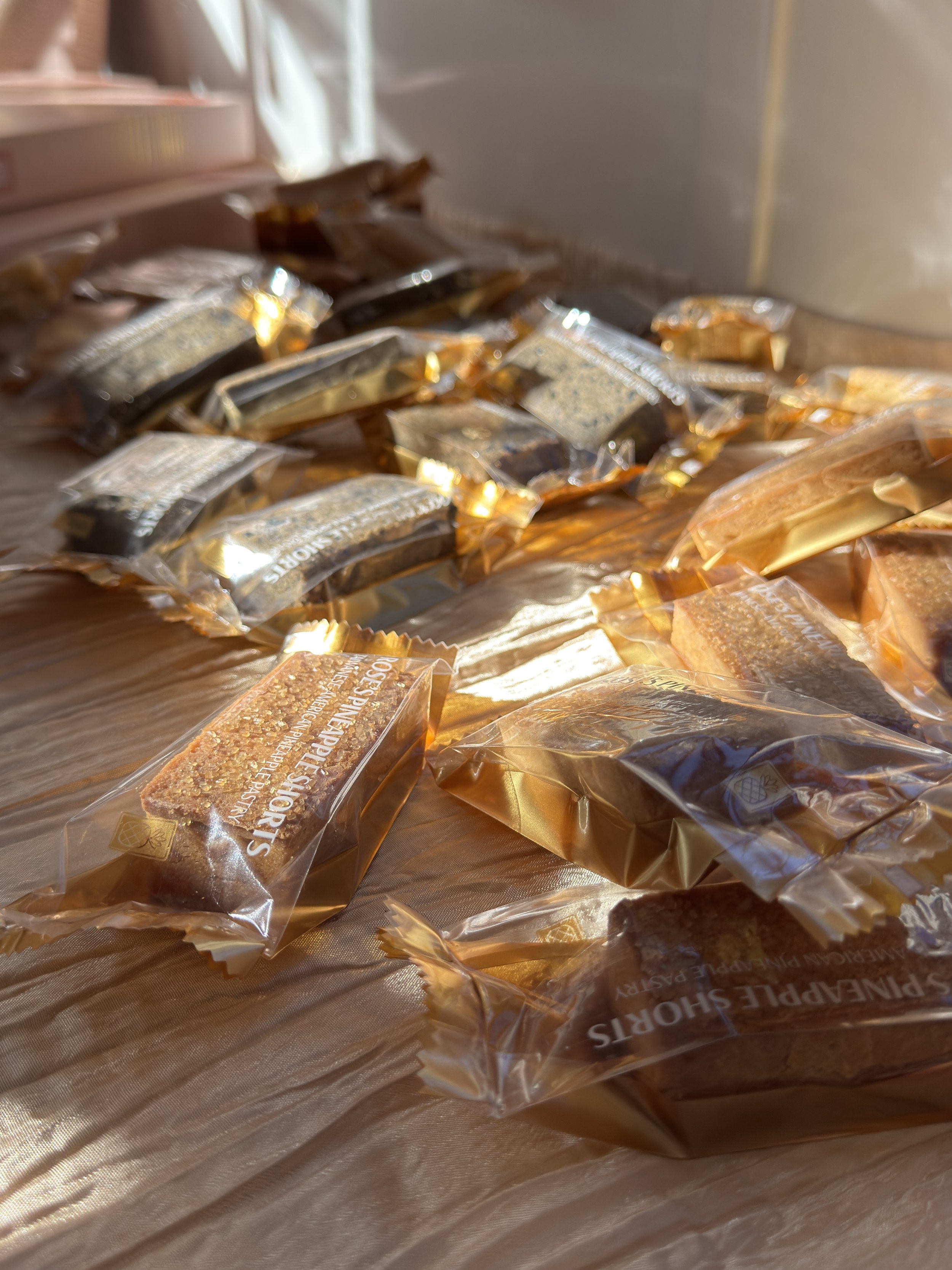 Several individually wrapped snack bars on a wooden surface, with sunlight shining on them.