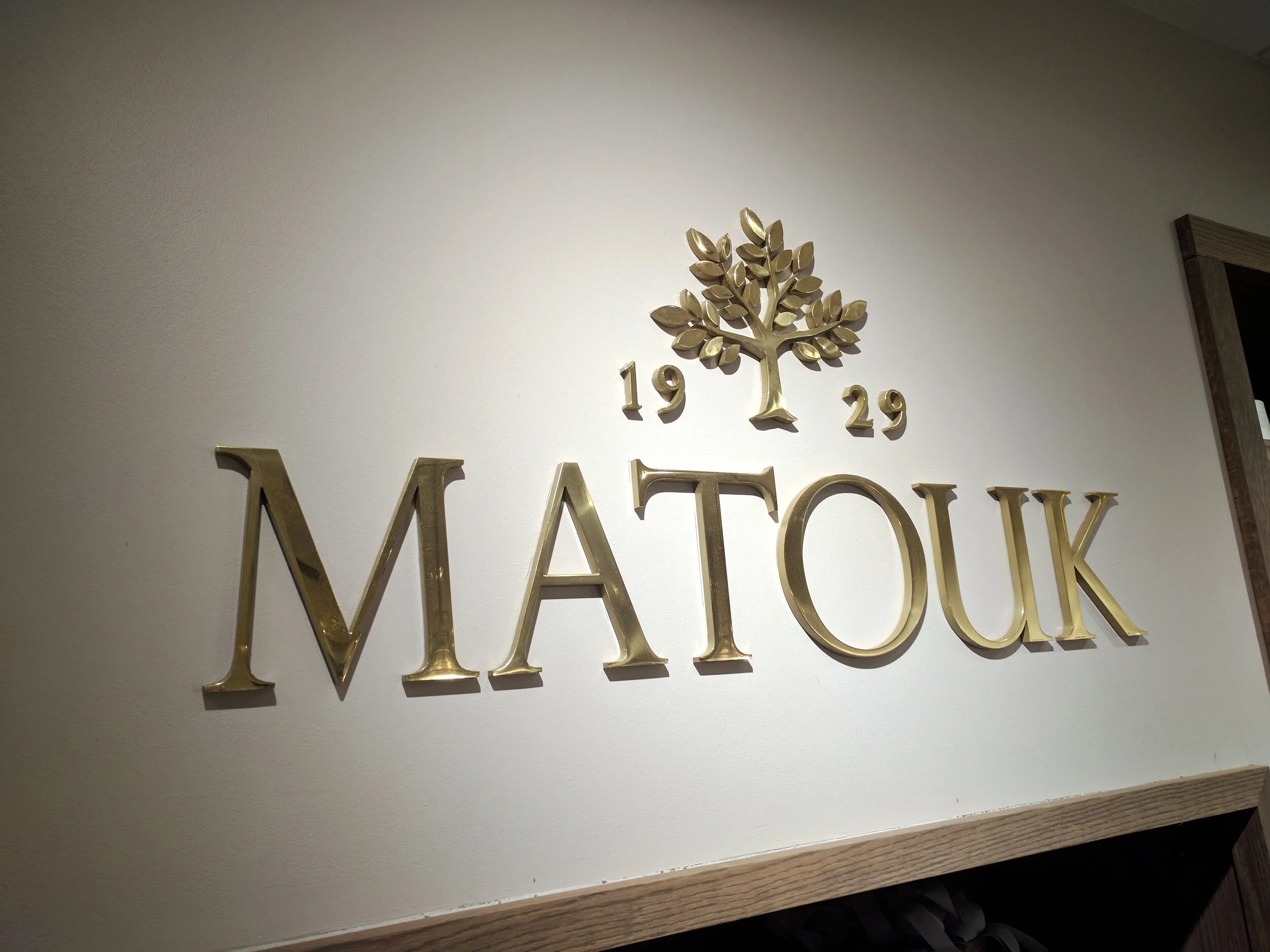 custom waterjet cut-out 1/4" thick dimensional individual mirror polished brass metal letters and logo pin-mounted to interior lobby reception wall in Midtown Manhattan in New York City, NY.