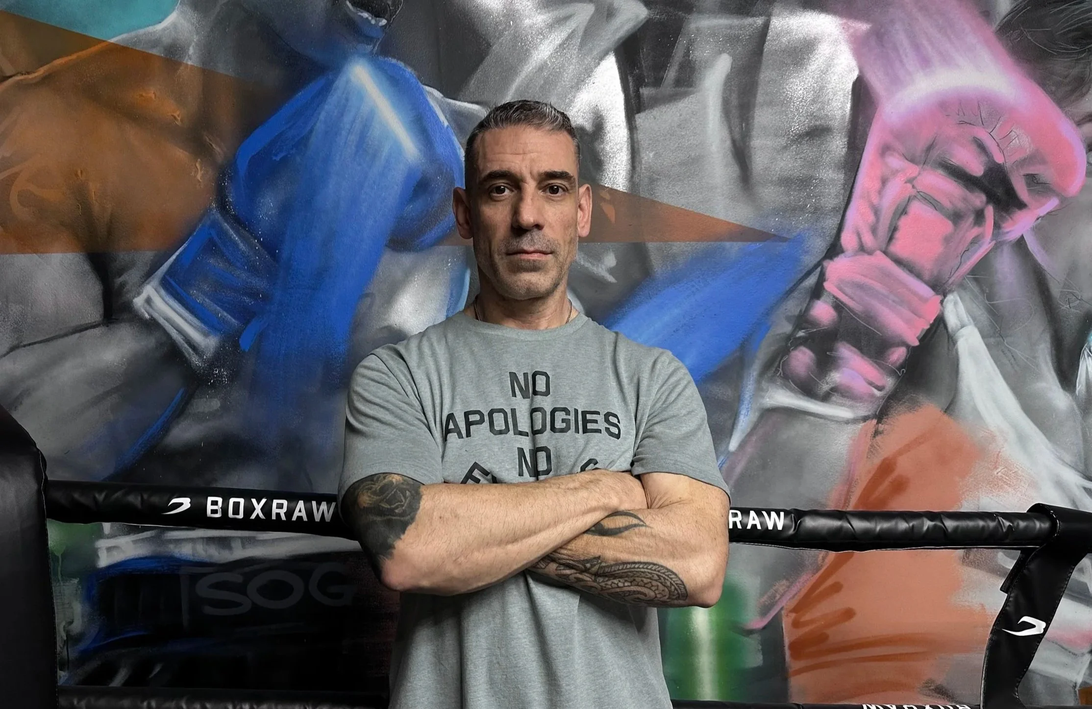 A person in a hoodie running on a paved pathway along a railing, with a cityscape and trees in the background, during daytime.