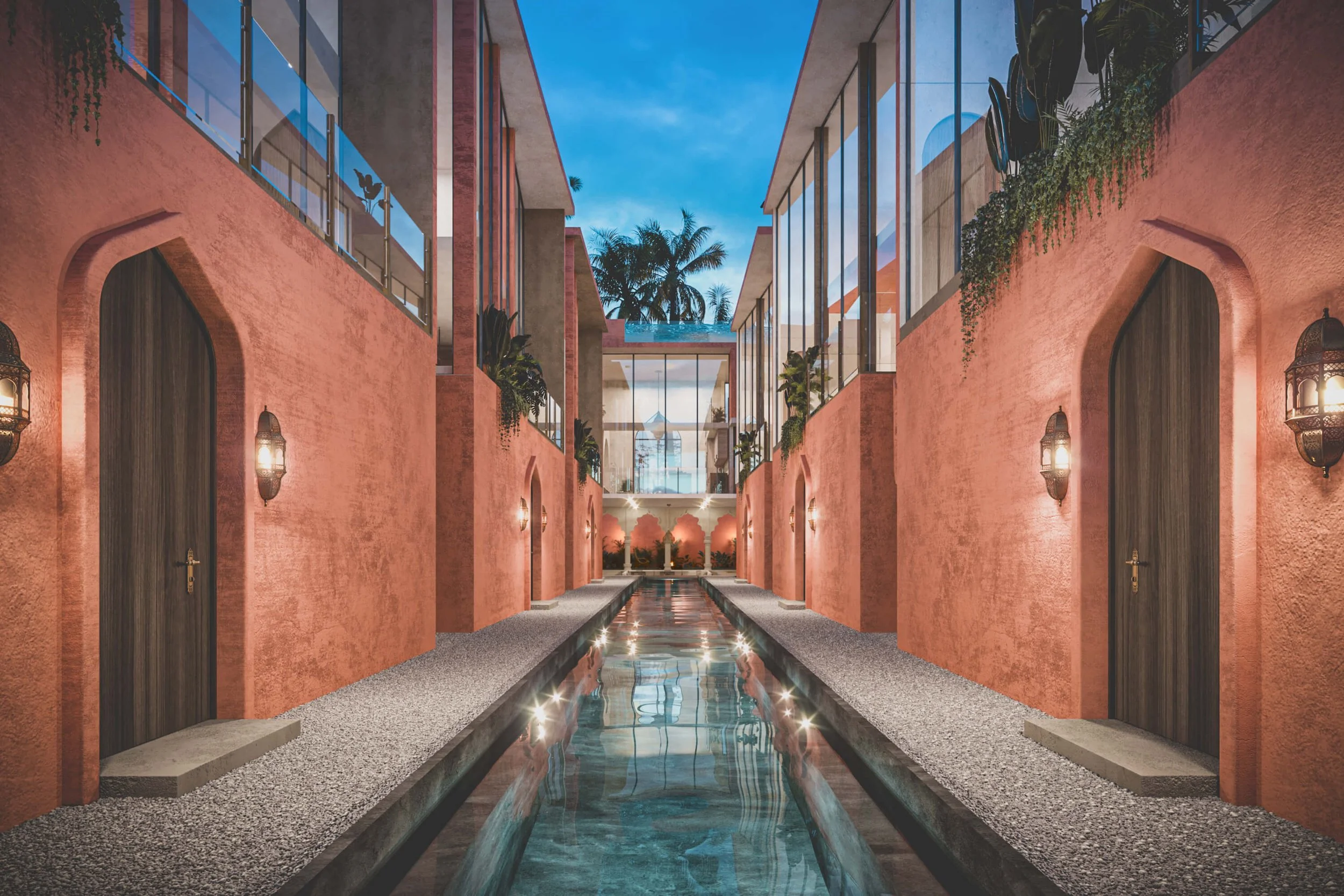 A modern, tropical hotel courtyard with a narrow water feature running through the center, pink stucco walls, wooden doors, outdoor lanterns, and balconies with glass railings, framed by palm trees under a twilight sky.