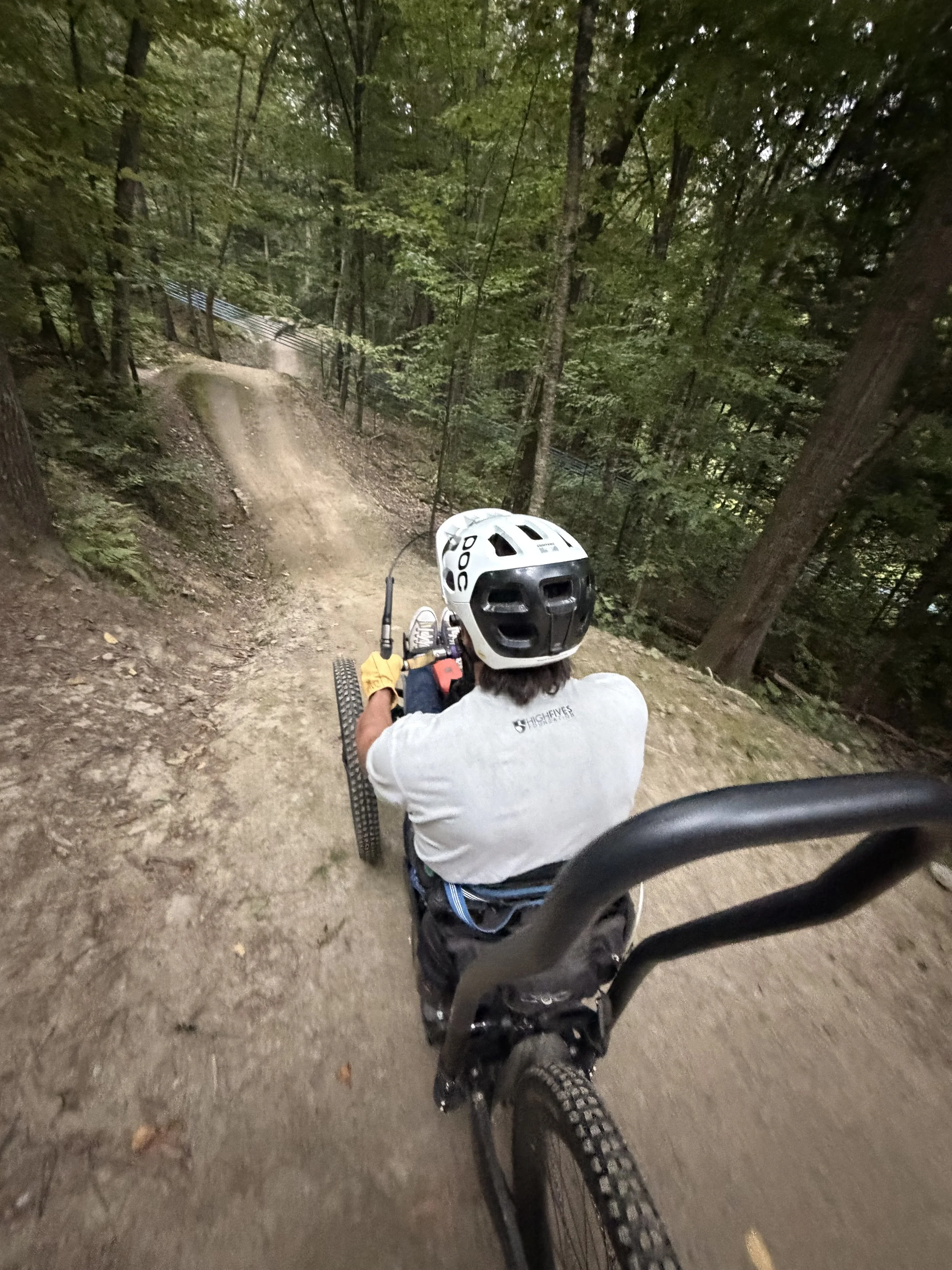 Louis Arevelo sits on his hand cycle bike starring down a rollercoaster looking dirt path.