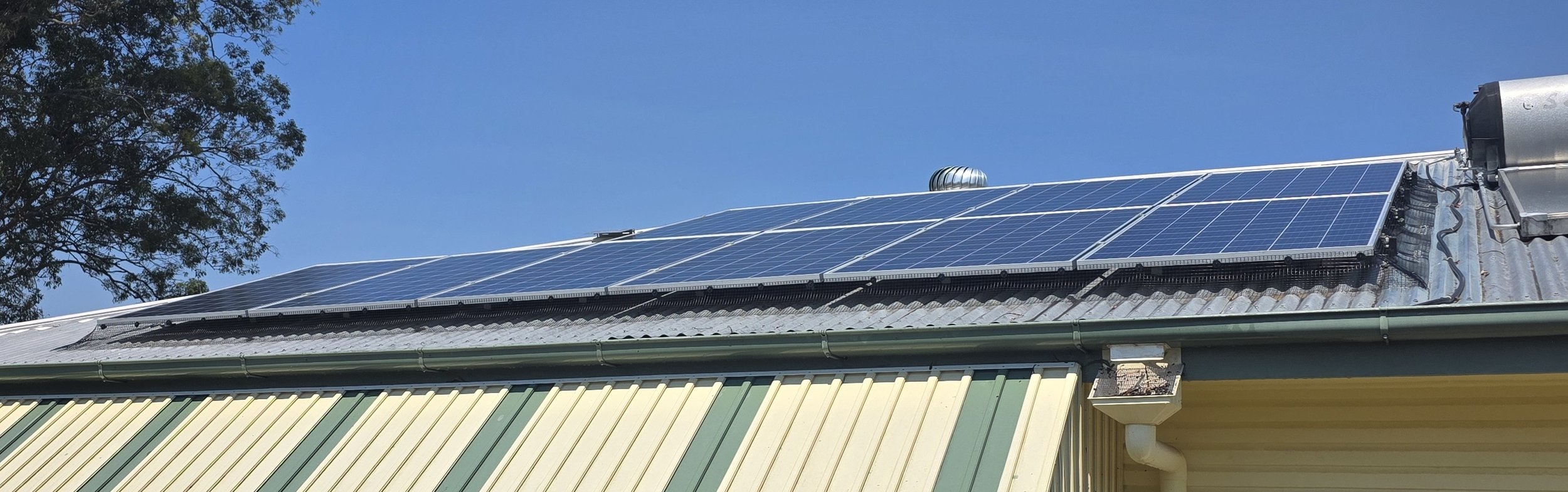 New bird proofing installed on rooftop solar panels to prevent birds nesting beneath them, with a clear blue sky in the background