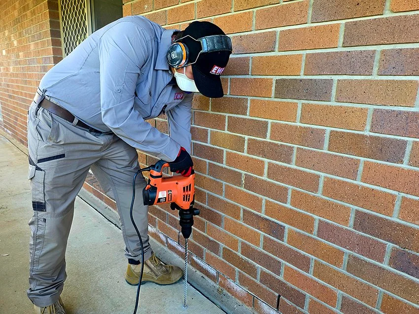 ben drilling a slab on external perimeter to stop termite mud going into house