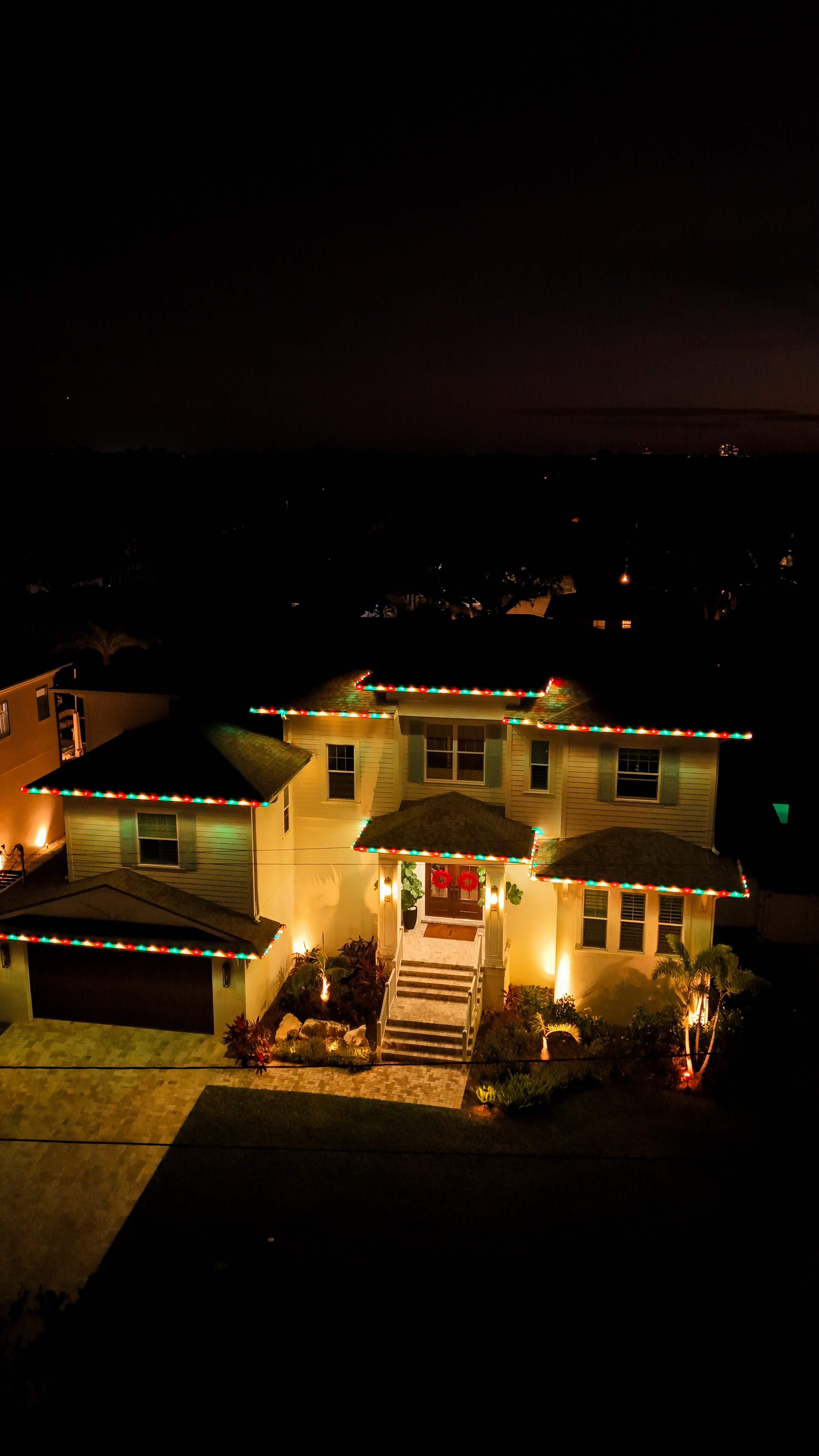 House decorated with colorful Christmas lights and wreaths at night