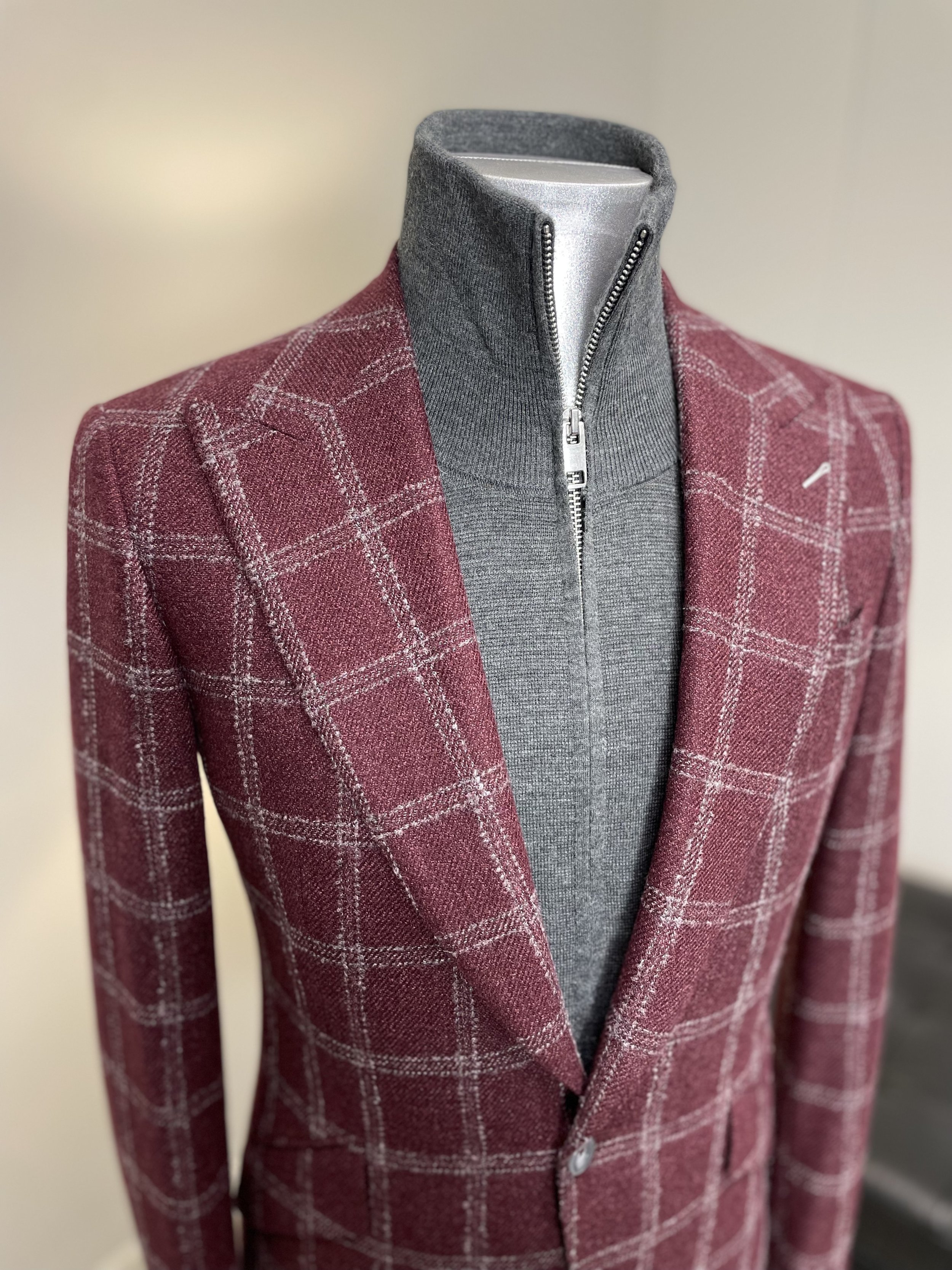 Red plaid blazer with a grey zip-up turtleneck on a mannequin.