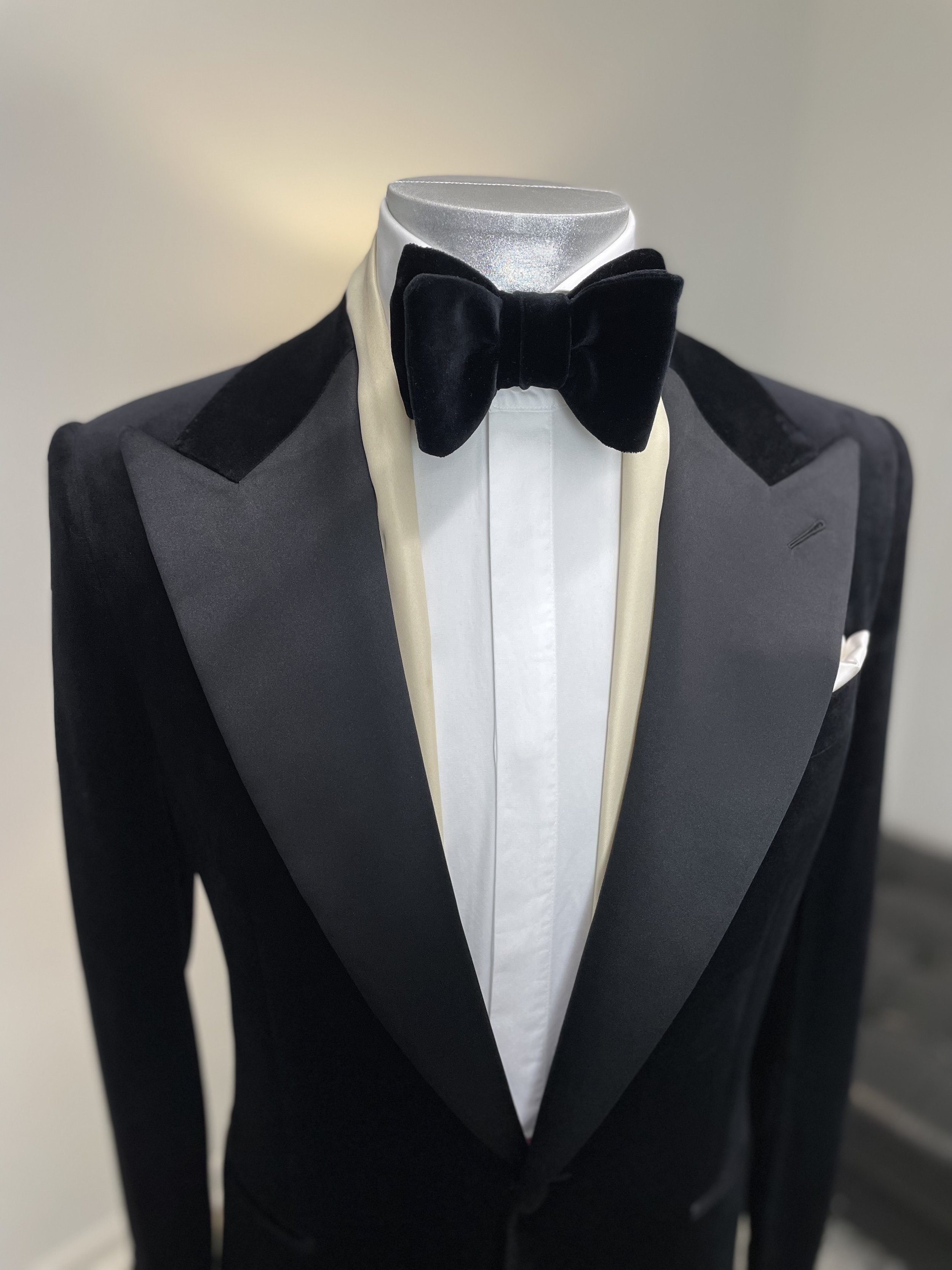 A tuxedo with a black velvet bow tie, white shirt, and black and gray jacket on a mannequin