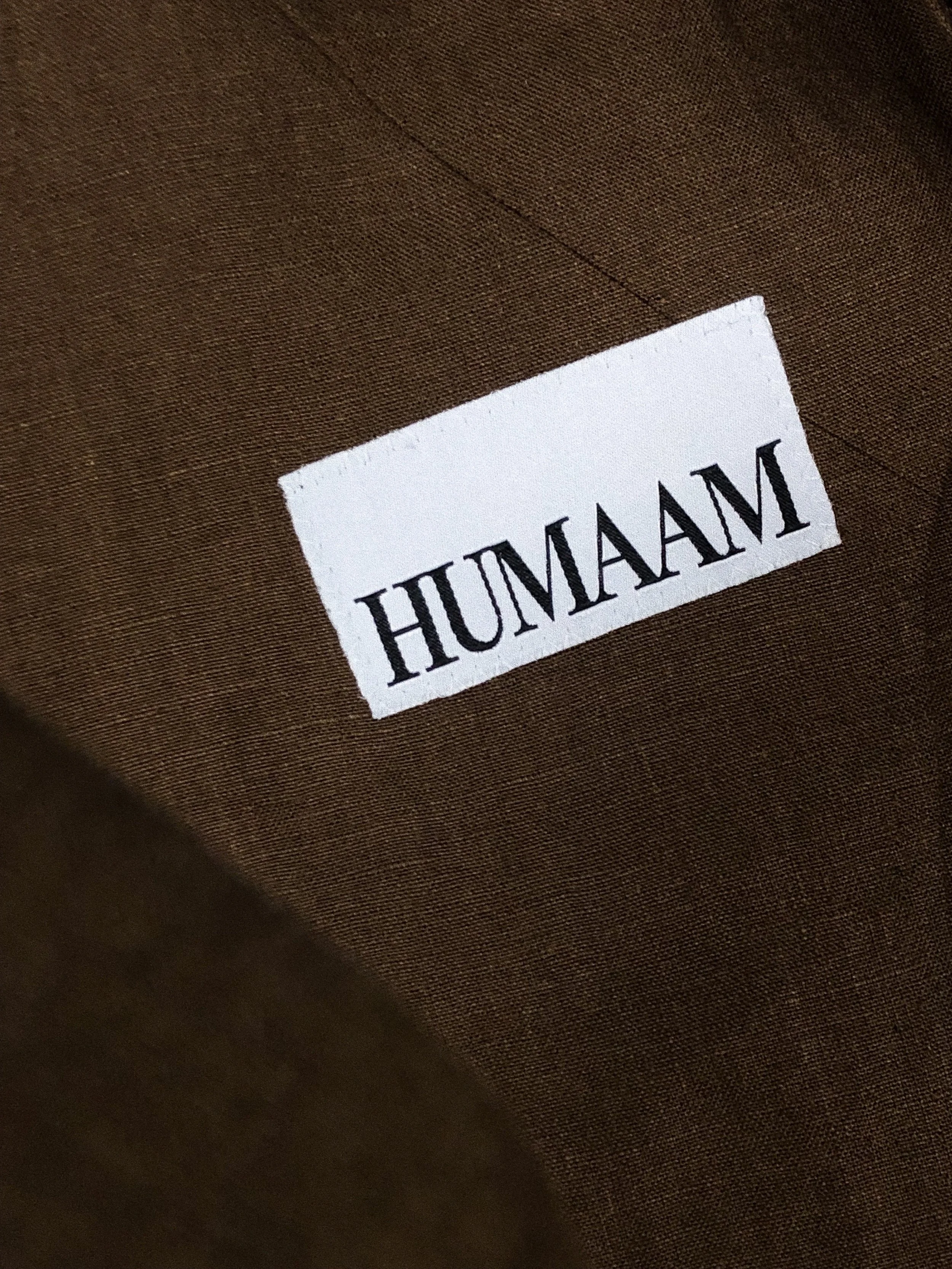 White label with the word 'HUMAN' printed upside down on brown fabric.