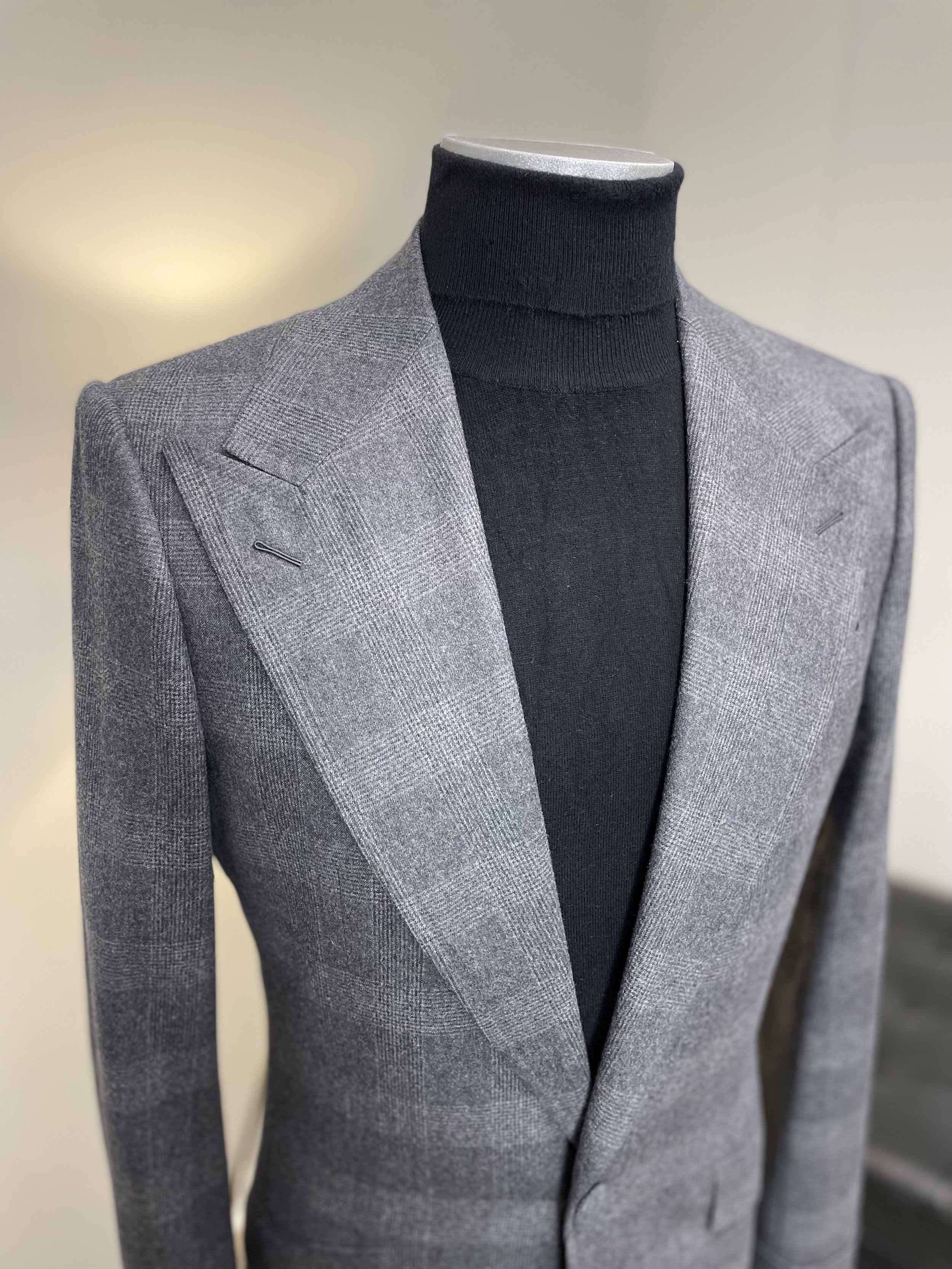 Gray checkered blazer on a mannequin with a black turtleneck underneath.