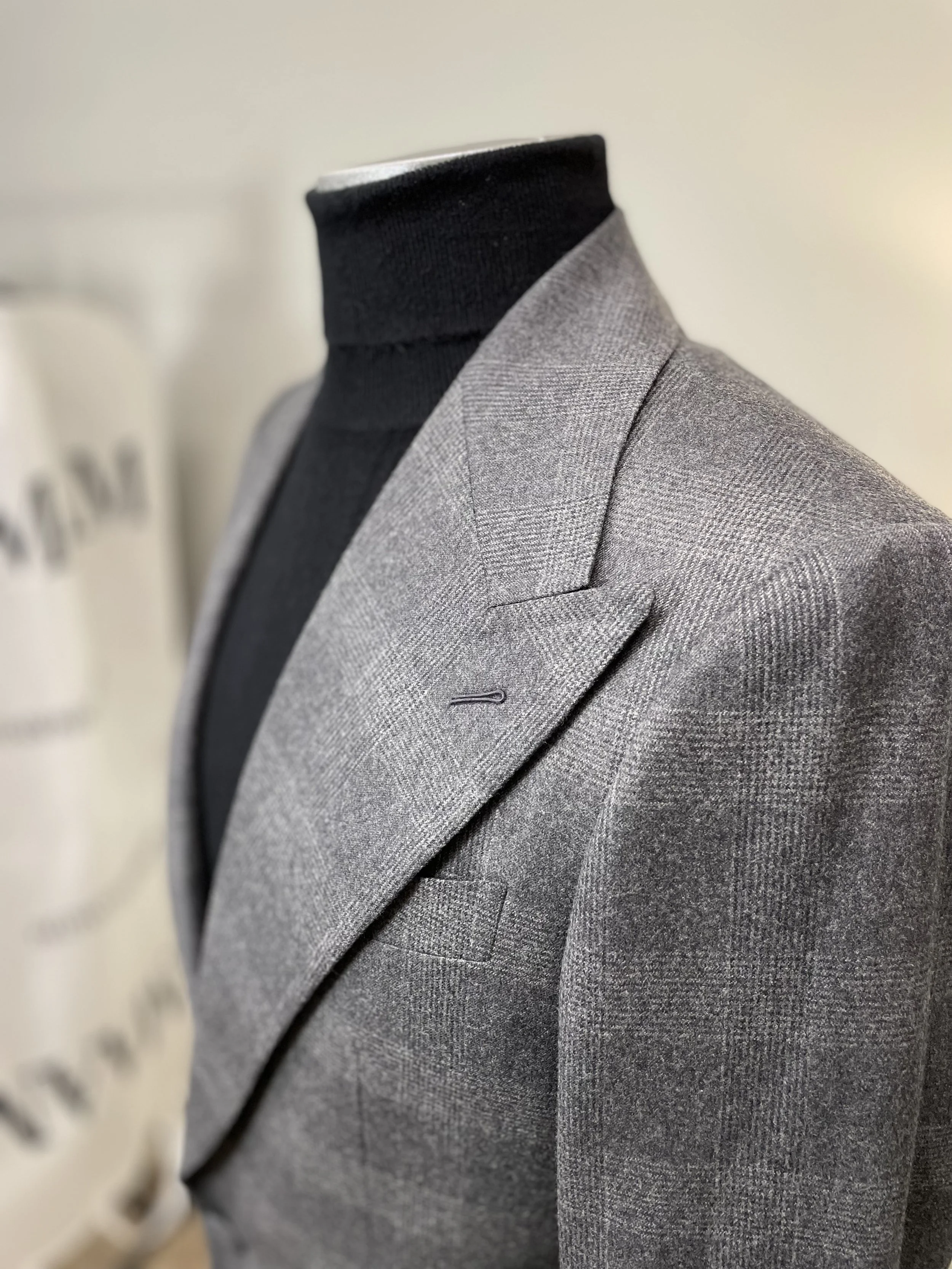 Gray suit jacket over a black turtleneck on a mannequin