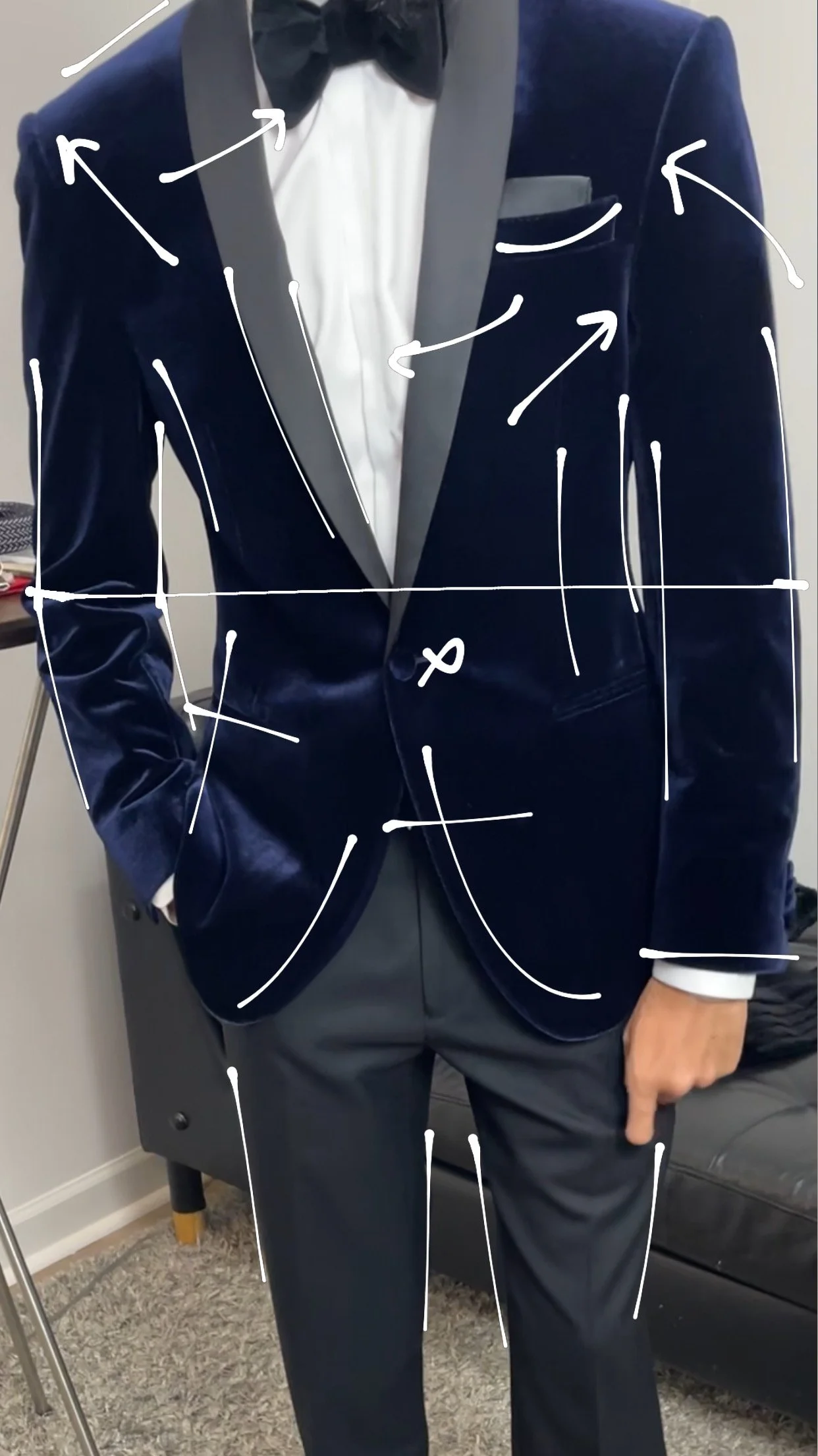A person wearing a navy blue tuxedo with a black bow tie and white dress shirt, with white arrows and lines drawn over the image for annotation.