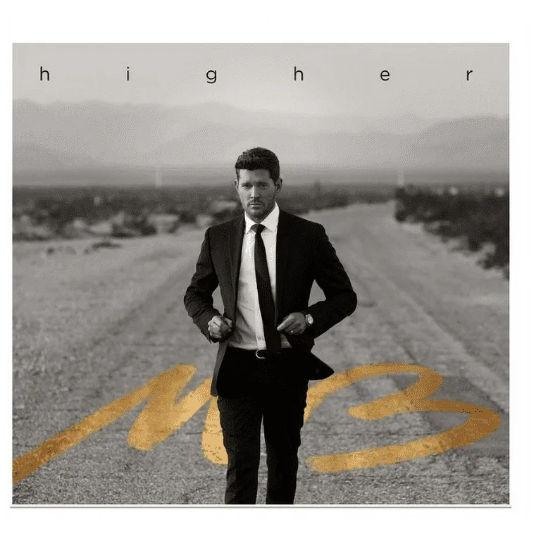 A black-and-white photo of a man (Michael Bublé) in a suit walking down a deserted road in a desert landscape. The word 'higher' is written at the top, and the word 'm3' is written in gold on the road.