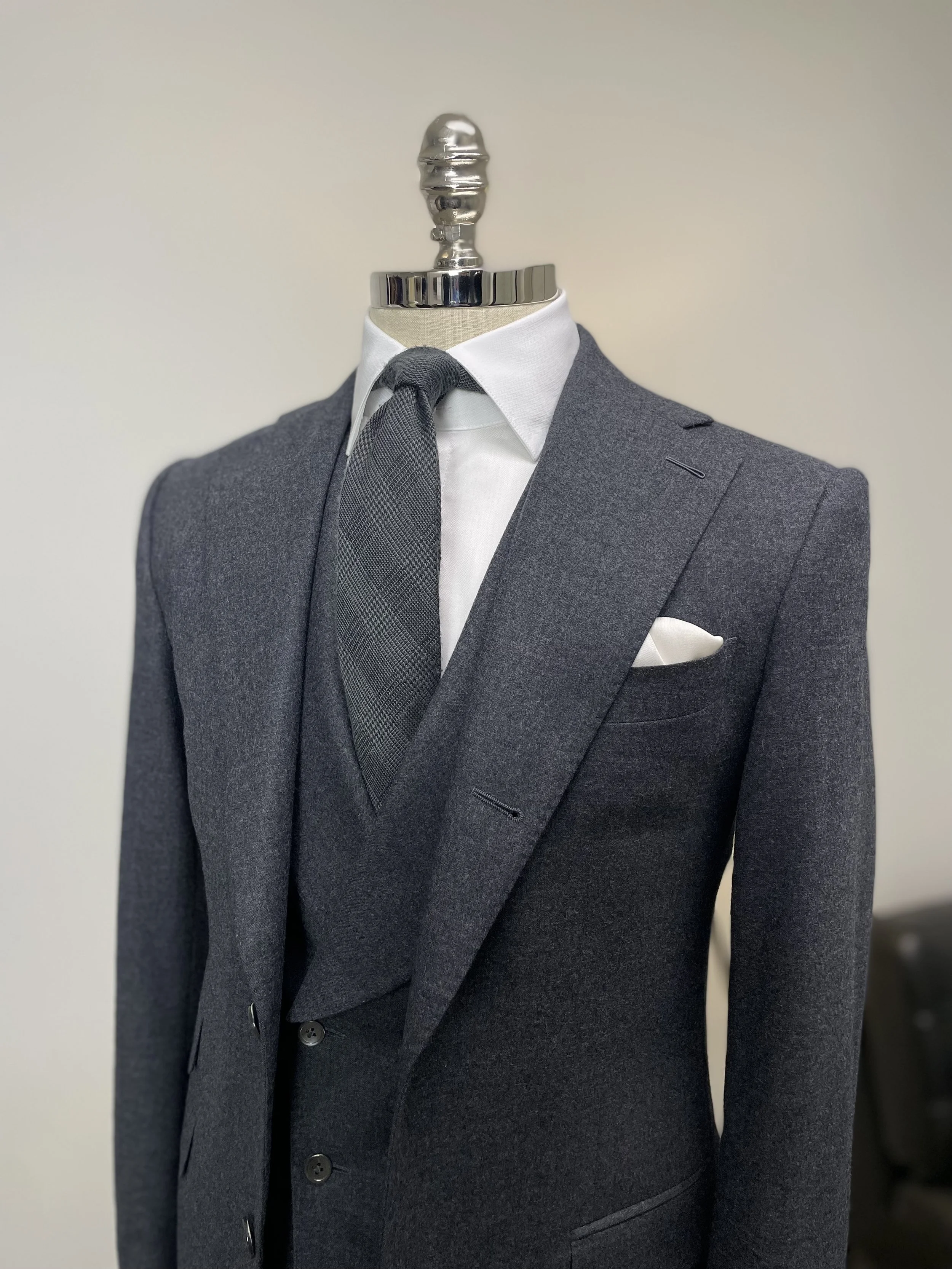 Gray suit on a mannequin with a white shirt, gray tie, and white pocket square.