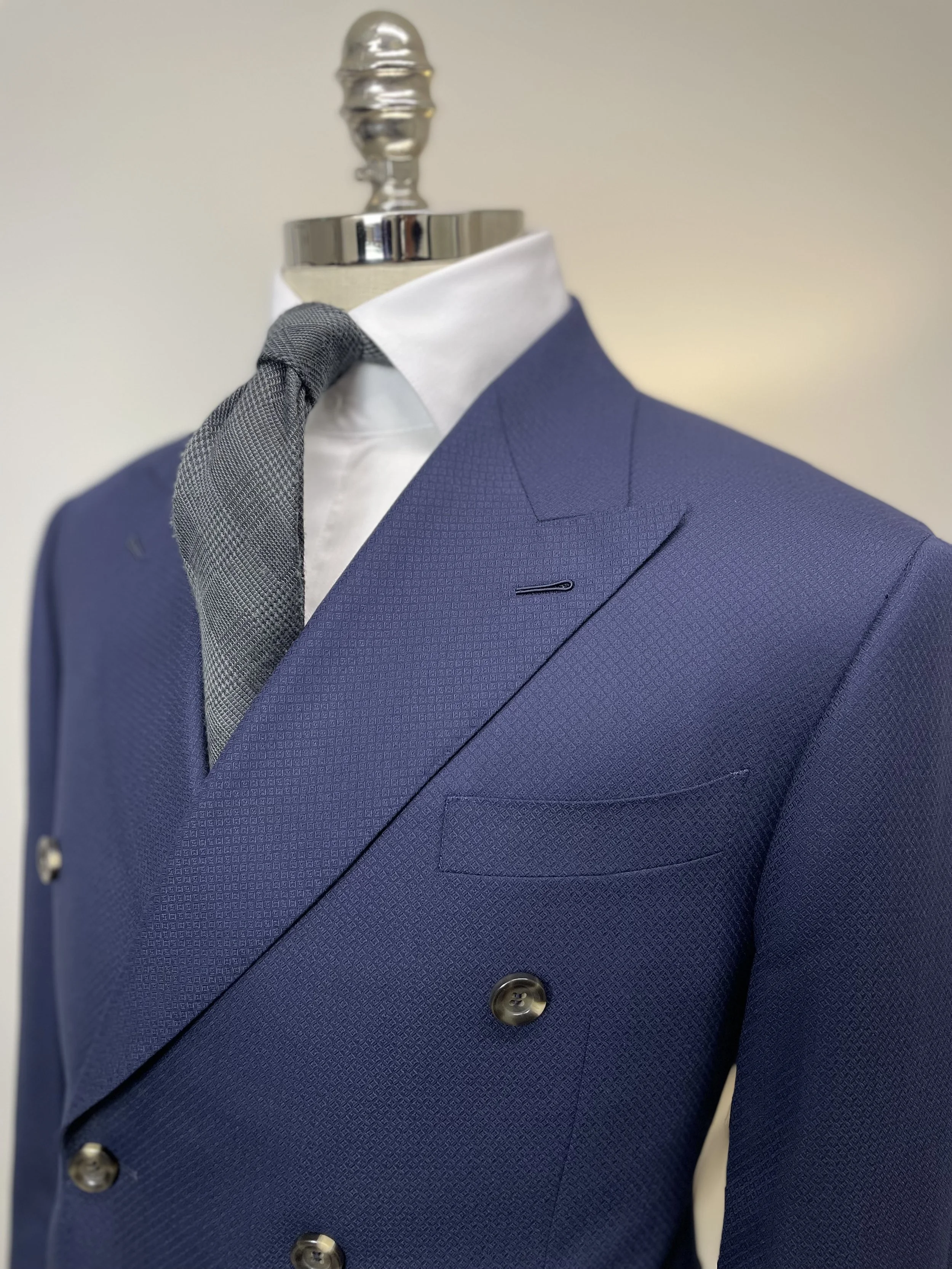 Mannequin wearing a blue double-breasted suit with a white shirt and a grey tie.