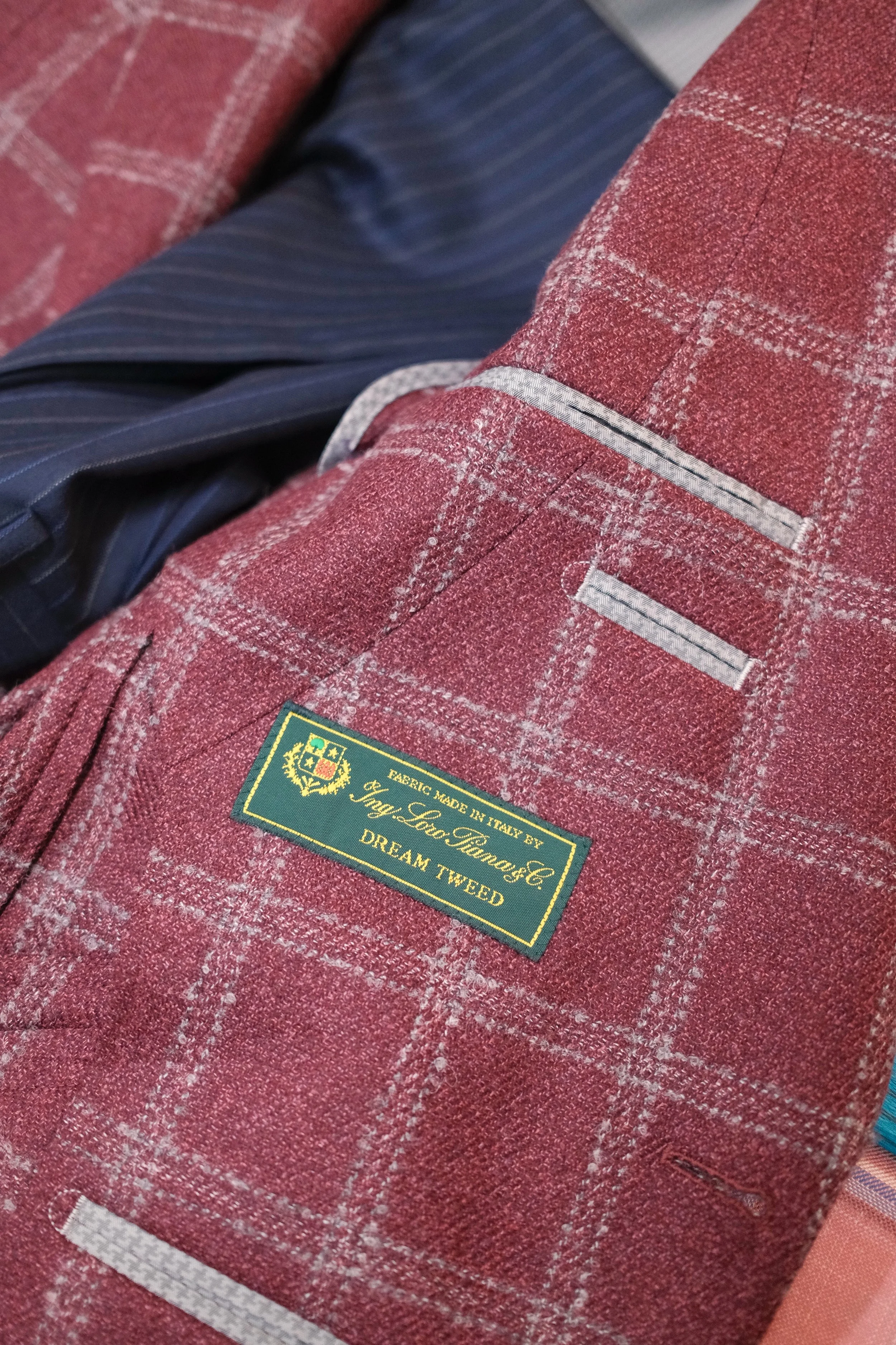 Close-up of a red checkered blazer with an inner label that reads "Italy, Fabrics Made in Italy by Tack Lo Tone & Co, Dream Tweed."