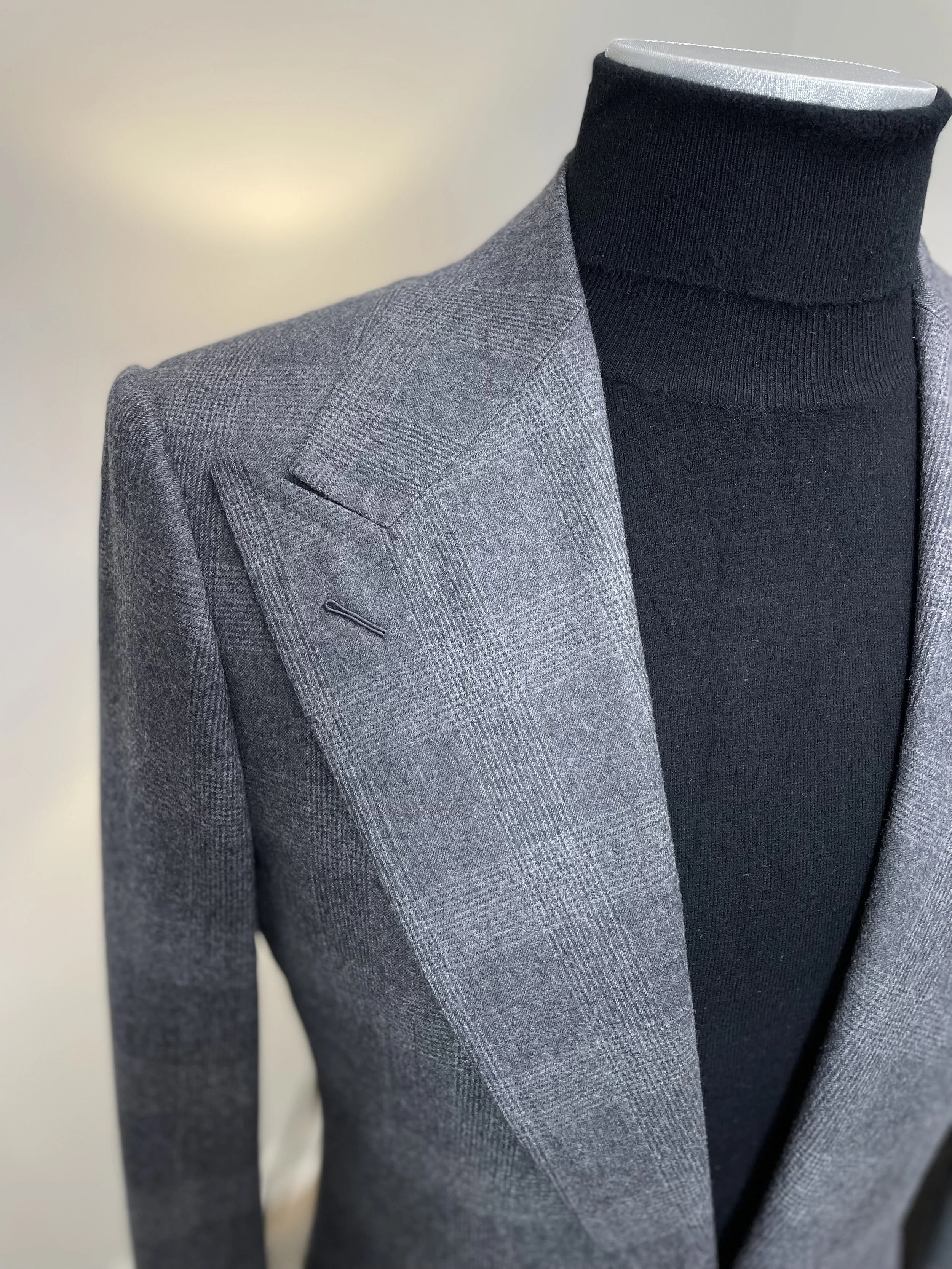 Close-up of a mannequin dressed in a gray checkered blazer and a black turtleneck.