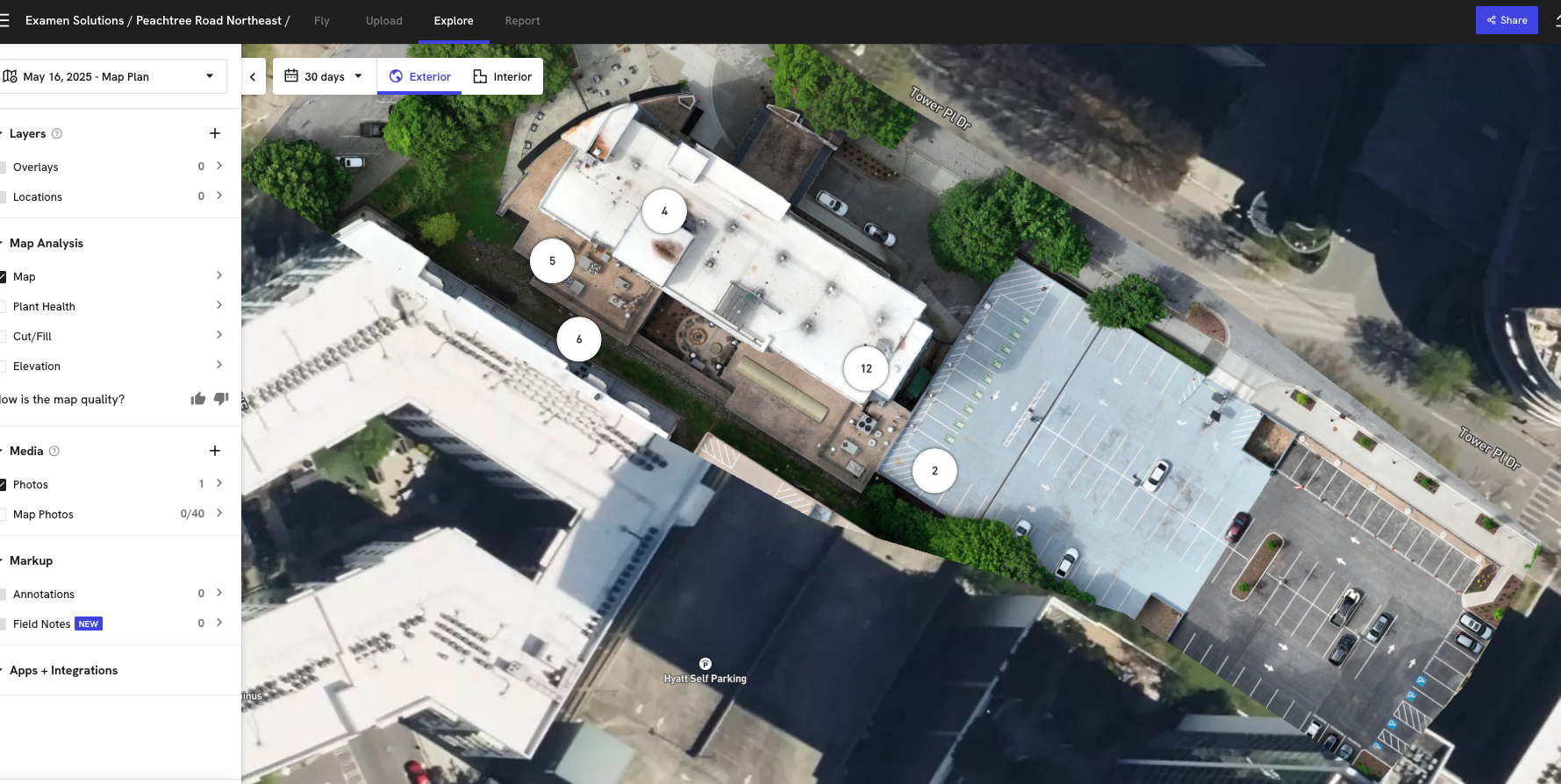 Aerial view of a rooftop building with numbered sections, adjacent parking lot, and surrounding trees.