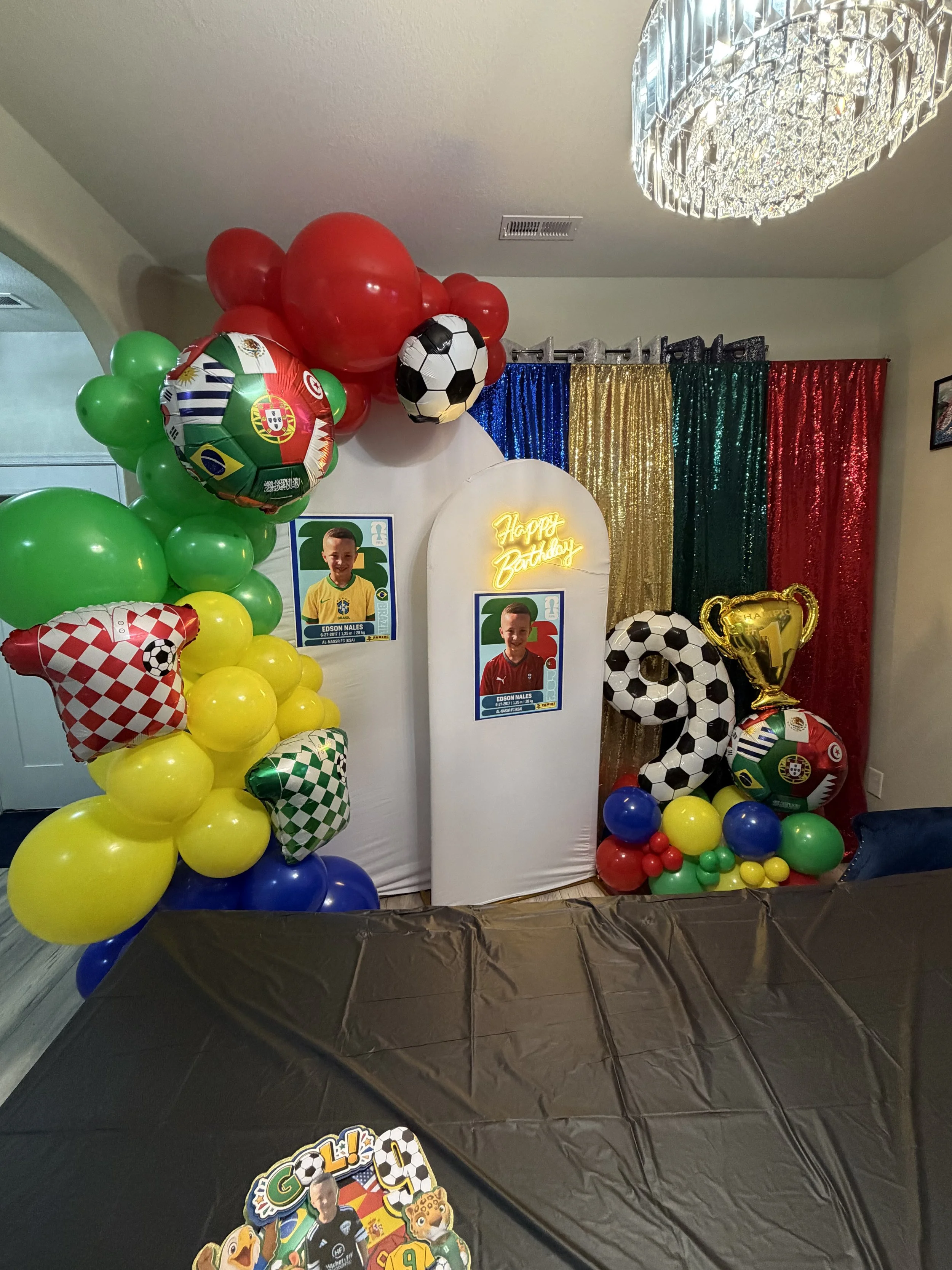 Honyes Booth Fifa World Cup Soccer/futbol Birthday Photo Booth rental set up in Hampton Roads Virginia with Red, Green, blue & Yellow Fifa World Cup Soccer/futbol balloon arch with player jerseys & Fifa World Cup Flag futbol/soccer ball balloons. 