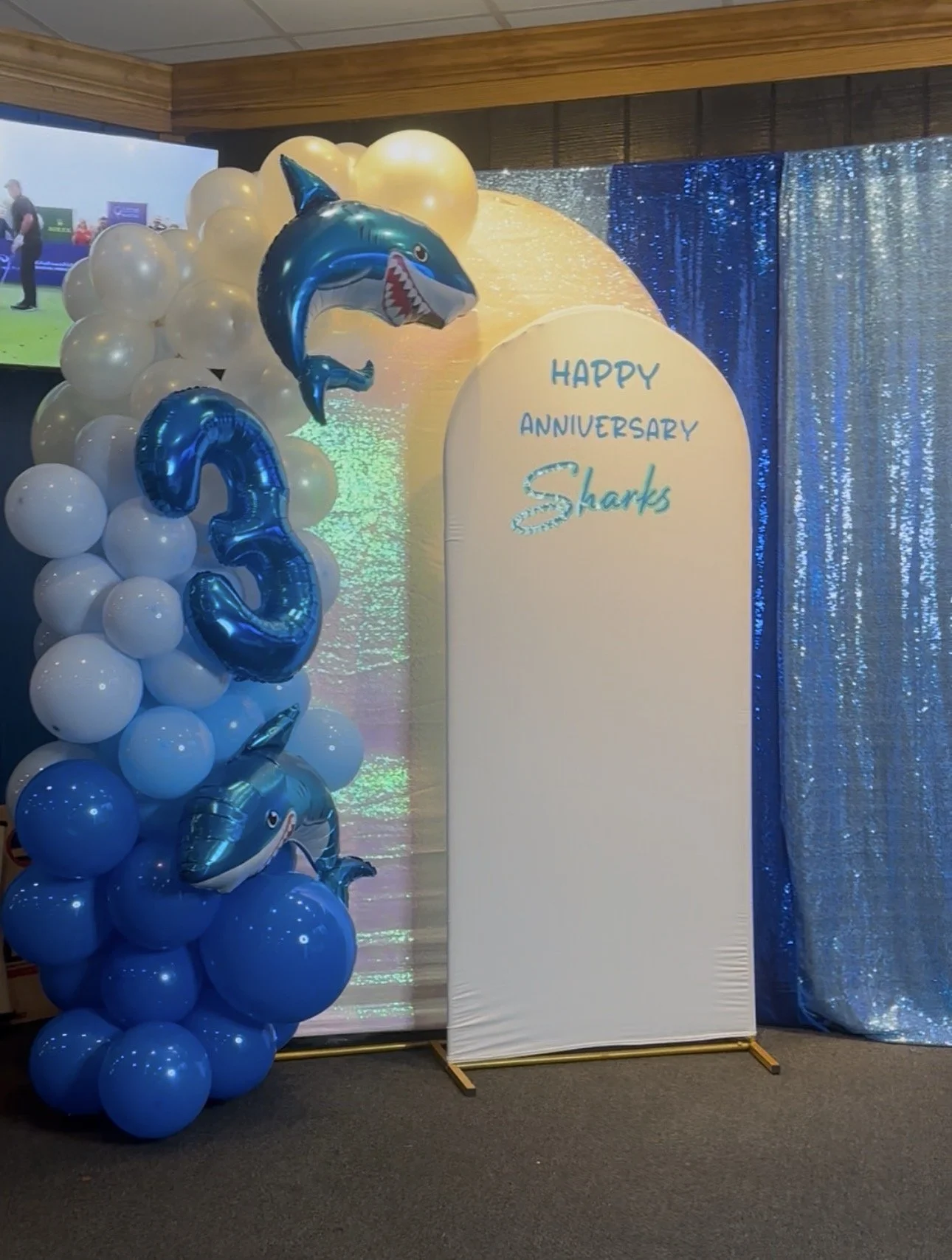 Honyes Booth Sharks Sports Bar Anniversary Photo Booth rental set up in Hampton Roads Virginia with White/opal and different shades of blues balloon arch for Sharks Sports Bar in Norfolk, VA 3rd anniversary. 