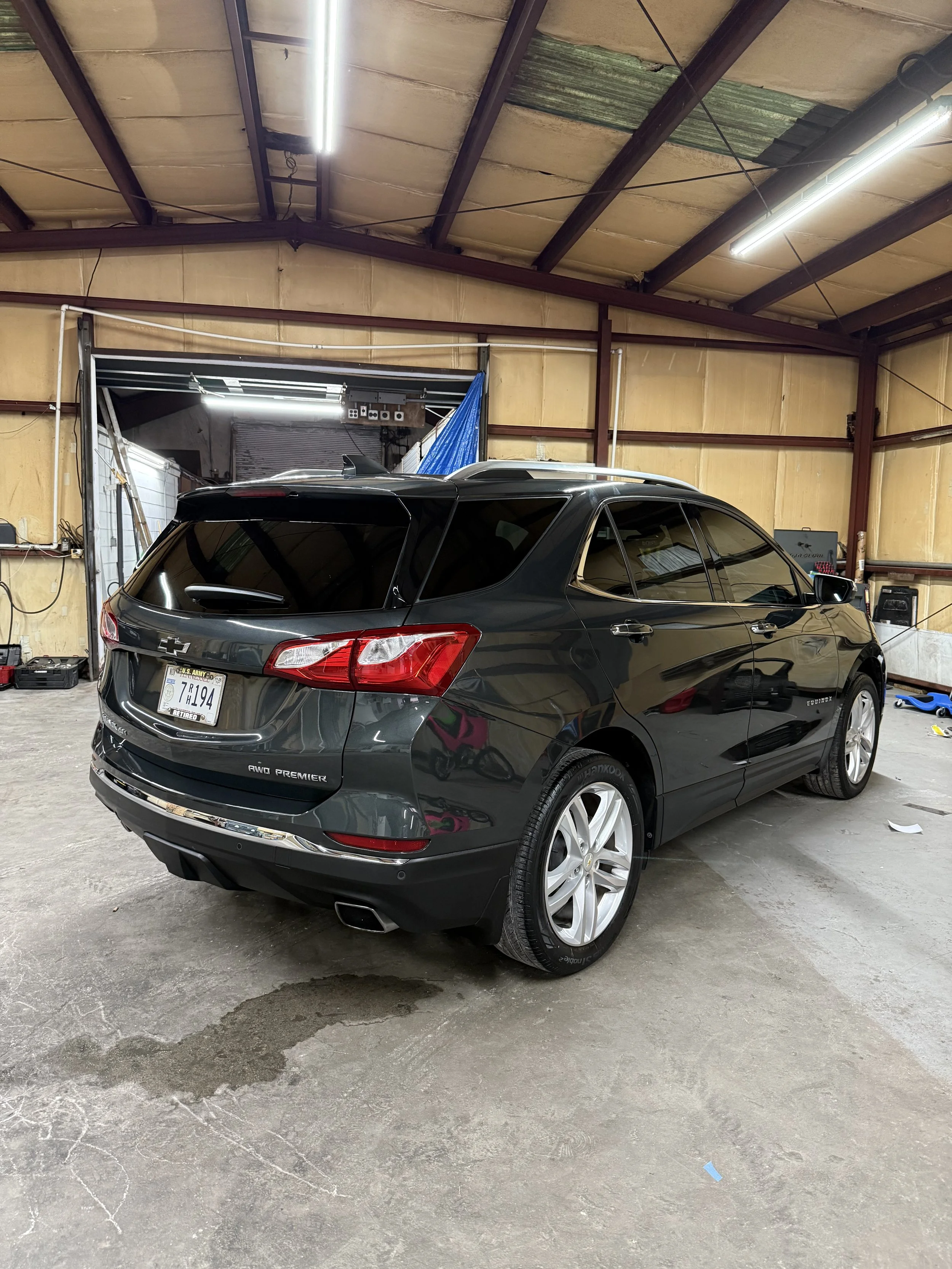 Black Chevrolet SUV parked inside a garage with a wet spot on the concrete floor.