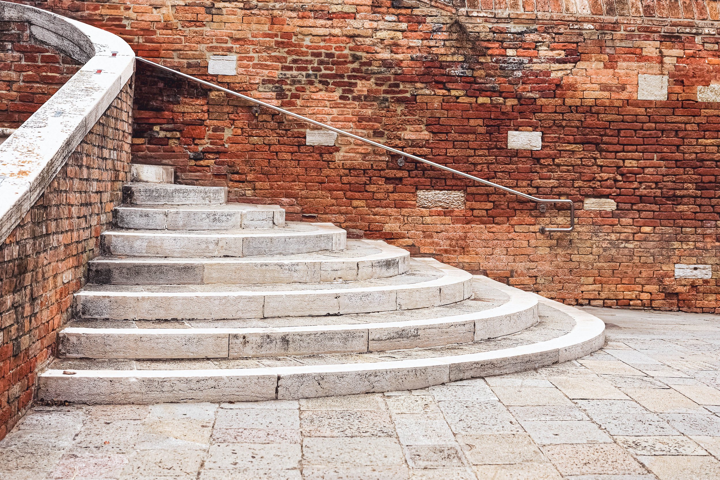 The curve holds quiet intention.
A sweep of steps pressed against Venetian brick,
where pause becomes pattern,
and history hums in the silence of stone.
For those who find rhythm in architecture and music in form —
this is a breath between stories.